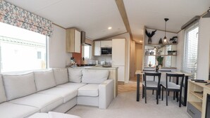 A modern, well-lit living area with a sofa, dining table, and kitchen in the background. - Giorgio (Preston)