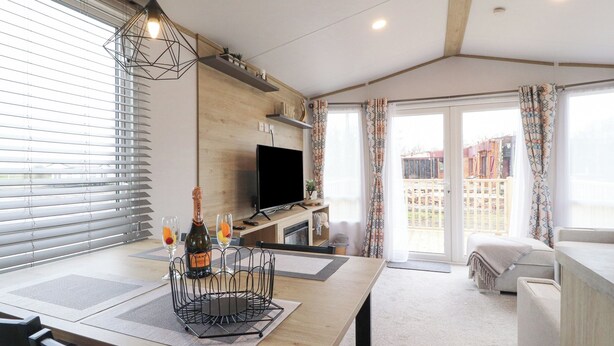 A modern living room with a wooden dining table, a TV, and a balcony with curtains. - Giorgio (Preston)