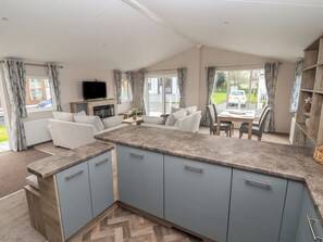 A modern kitchen with grey cabinets, a herringbone floor, and a dining area with a table and chairs. - Lodge 9 (Saint Asaph)