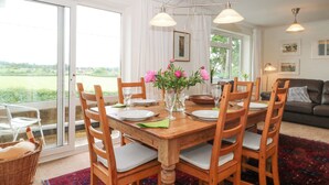 A dining area with a wooden table, chairs, and a vase of flowers. - Plum Hill (Oswestry)