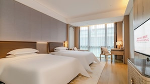 Une chambre d’hôtel avec deux lits, un bureau, une chaise et un écran de télévision.