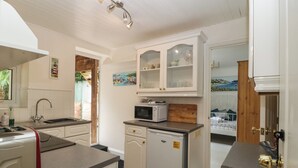 A compact kitchen with white cabinetry, a built-in microwave, and a small refrigerator.