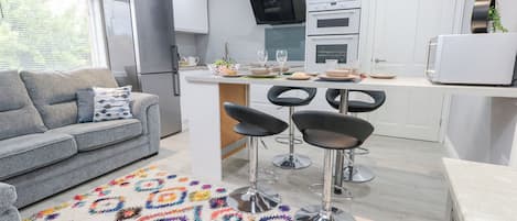 A modern kitchen with white cabinets, a built-in oven, and a TV mounted above the counter.