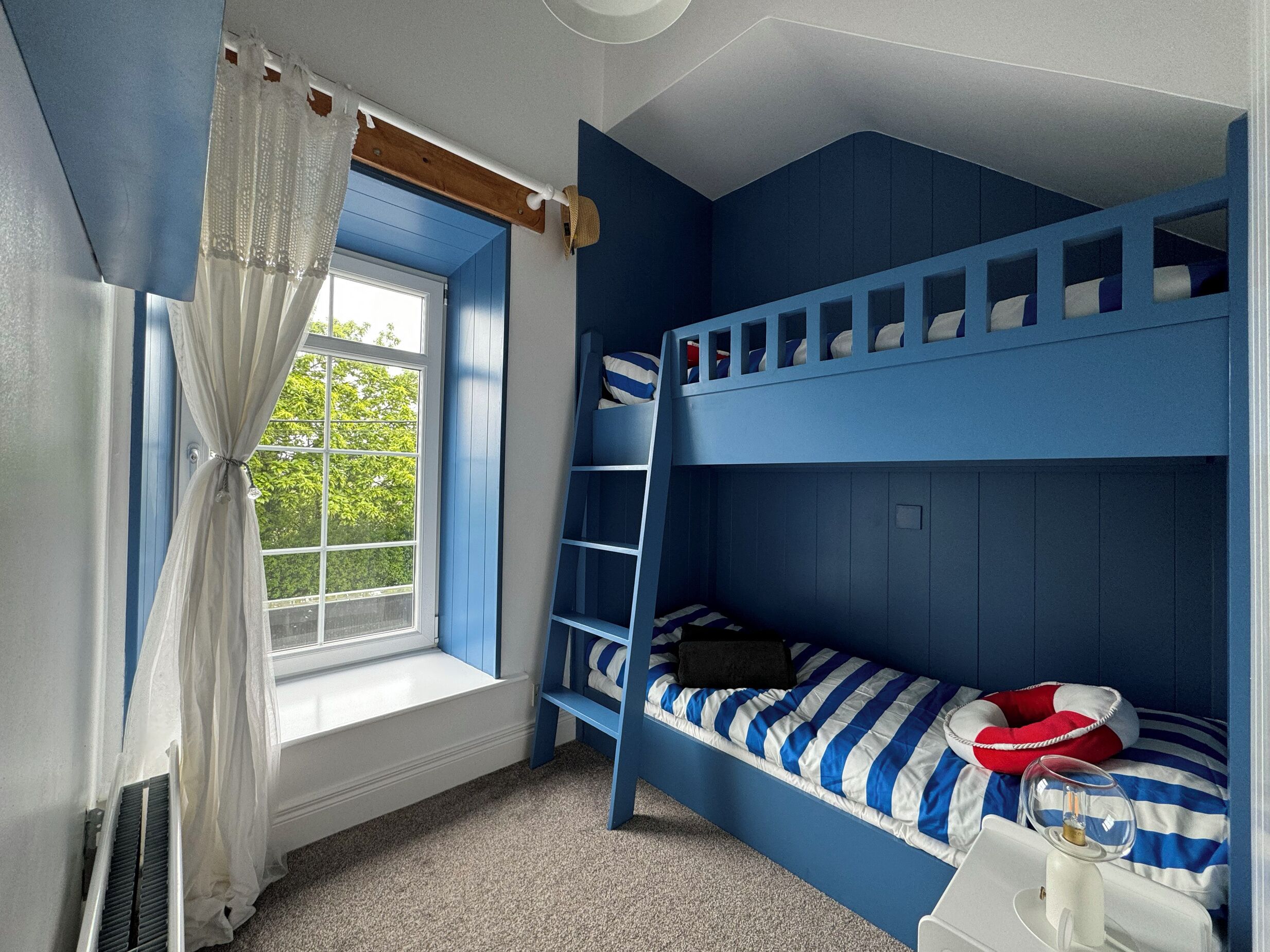 Ein Zimmer mit Etagenbett, einem Vorhangfenster und einem Heizkörper.