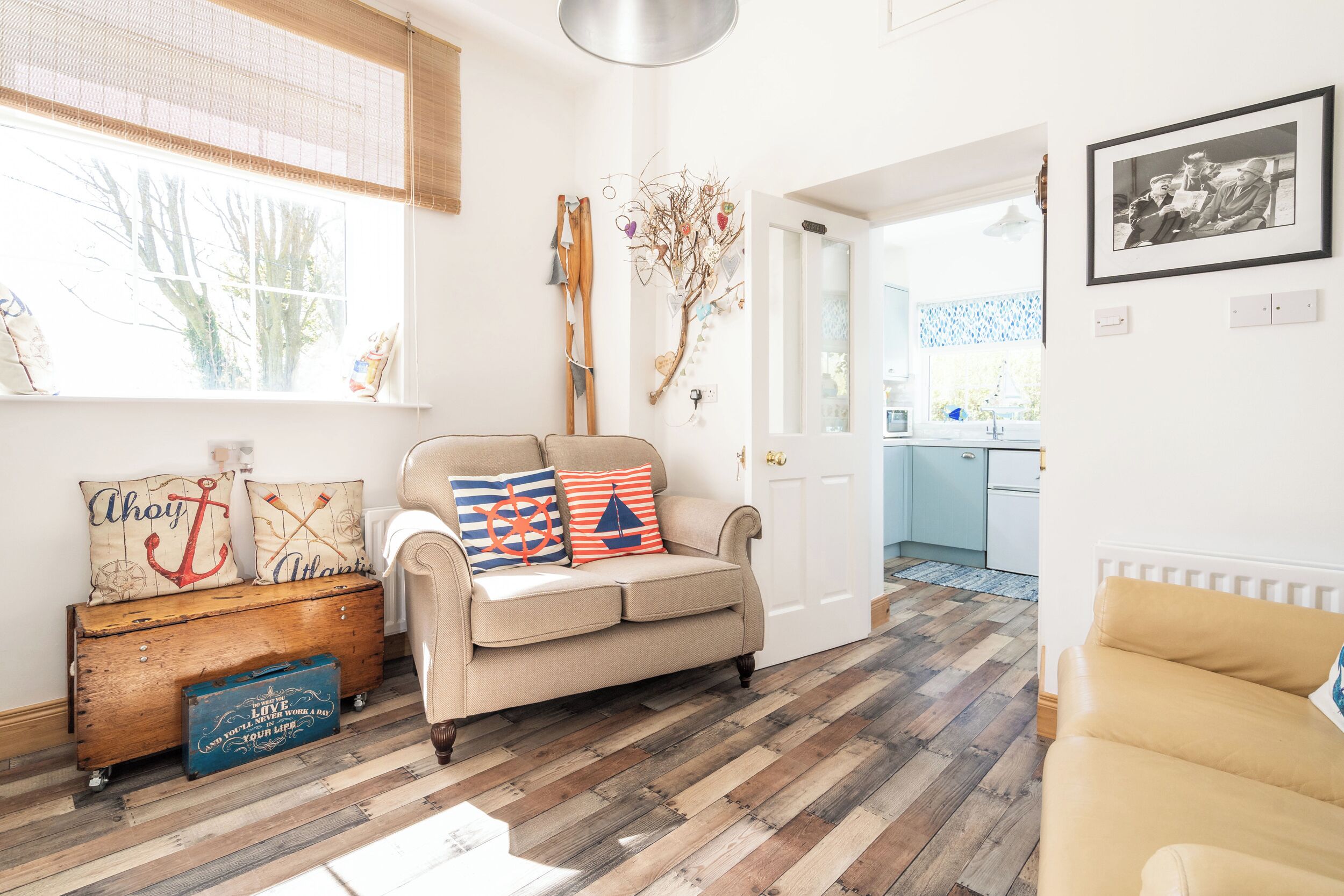 A living room with a beige sofa, wooden floor, and nautical-themed decor.