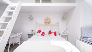 Ein Schlafzimmer mit einem Bett, einem weißen Sessel, einem Nachttisch, einer Kommode, einem Hut an der Wand und einer Leiter.