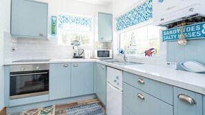 Eine Küche mit hellblauen Schränken, einer weißen Arbeitsplatte, einer Mikrowelle, einem Backofen und einem Spülbecken.
