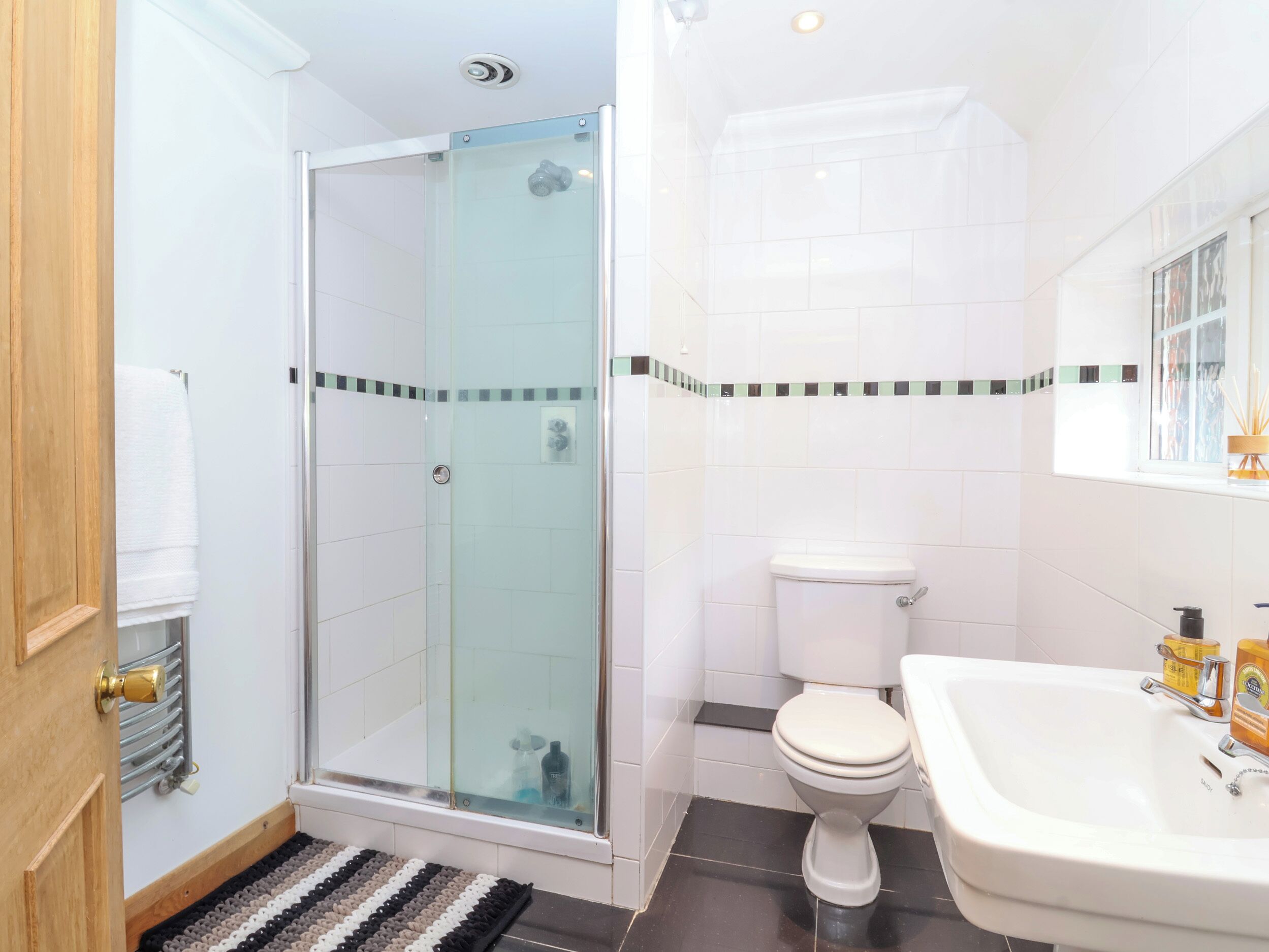 Une salle de bain avec une douche à parois de verre, des toilettes blanches et un lavabo avec un miroir au-dessus.