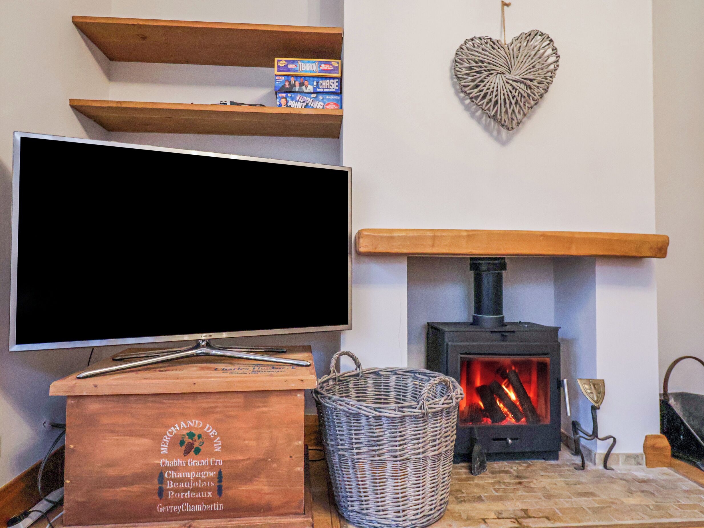A living room with a flat-screen TV, a fireplace, and wooden shelves.