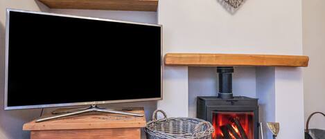 Ein Wohnzimmer mit Flachbildfernseher, Kamin und Holzböden.