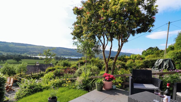 A patio with outdoor furniture, a potted plant, and a view of a lush landscape. - Lavender Cottage (Coniston)
