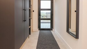 Un couloir avec une porte sombre, un plafond en bois et un sol recouvert de moquette.