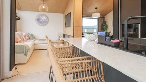 Une cuisine moderne avec un coin bar, un plafond en bois et un espace repas comprenant un canapé et des chaises.