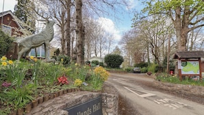 A sign for Woodlands Hall Caravan Park with a stone wall and a horse statue. - Woodlands Lodge (Ruthin)