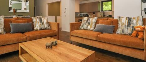 A modern living room with two sofas, a coffee table, and a kitchen in the background.