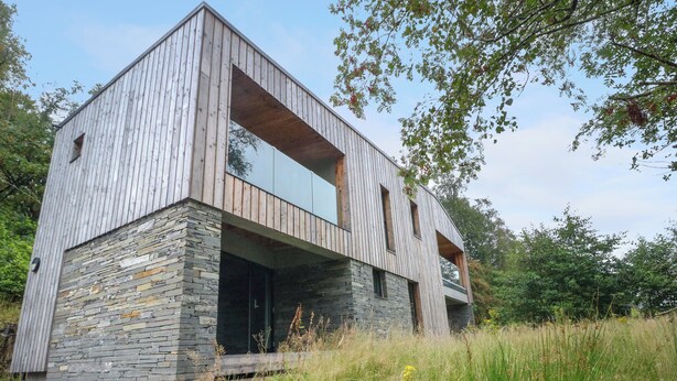 A modern two-story house with a stone foundation and wooden exterior.