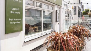 A storefront with a sign reading "The Olive Tree" and a green signboard stating "Licensed Restaurant Fresh & seasonal local produce". - Flat 2 Niles Place (Padstow)