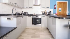 A modern kitchen with white cabinets, a black countertop, and a built-in oven. - Flat 2 Niles Place (Padstow)