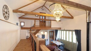 Ein geräumiger Loftraum mit einer Holztreppe, einem Chandelier und einer Essecke mit Blick.