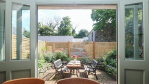 Eine offene Terrasse mit Tisch und Stühlen, umgeben von einem Holzzaun und einem Garten.