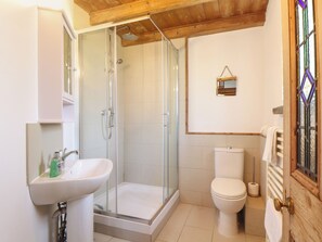 A bathroom with a glass-enclosed shower, a white sink, and a toilet. - Bert's Barn (Helston)