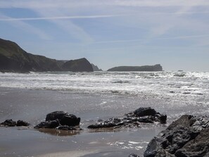 A beach with rocky terrain and waves. - Bert's Barn (Helston)