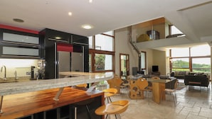 Cocina moderna con barra, ventanas amplias y zona de comedor con taburetes de bar.