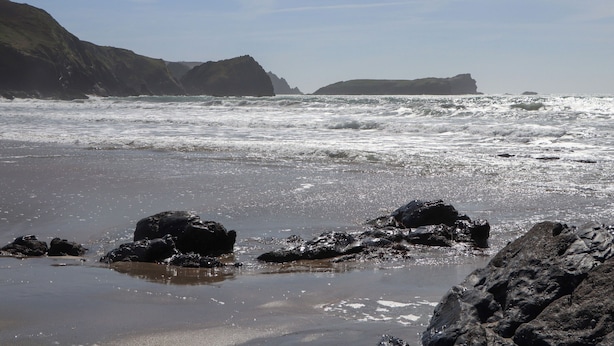 Uma praia com terreno rochoso e ondas.