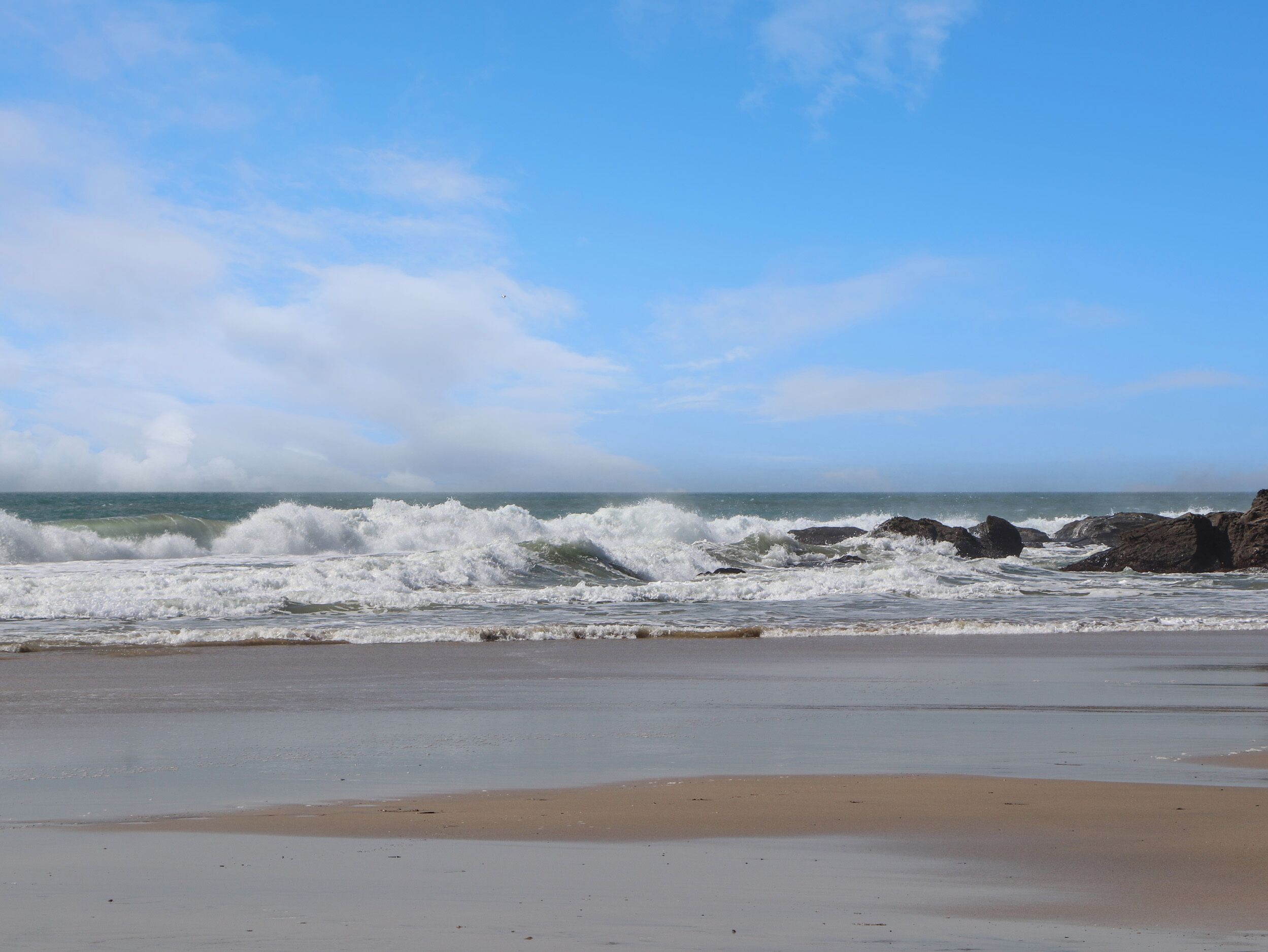 Una playa con olas rompiendo en la orilla y un cielo despejado.