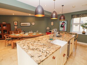 A kitchen with a granite countertop, wooden cabinets, and pendant lighting. - Homestead (High Peak)