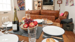 A dining area with a table set for two, featuring a bottle of wine, a bowl of grapes, and a plate of food. - Fisherman's Cottage, King Street (Portland)