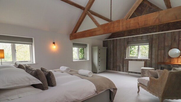 Een slaapkamer met een groot bed, een kast, een stoel en een raam.
