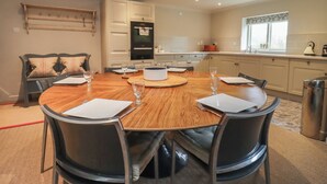 Een eetgedeelte met een ronde houten tafel, zwarte stoelen en een witte decoratie.