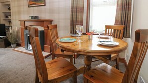Ein Essbereich mit einem runden Holztisch, vier Holzstühlen und einem Gemälde an der Wand.