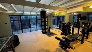 Een sportschool met diverse fitnessapparaten, grote ramen en een bokszak.