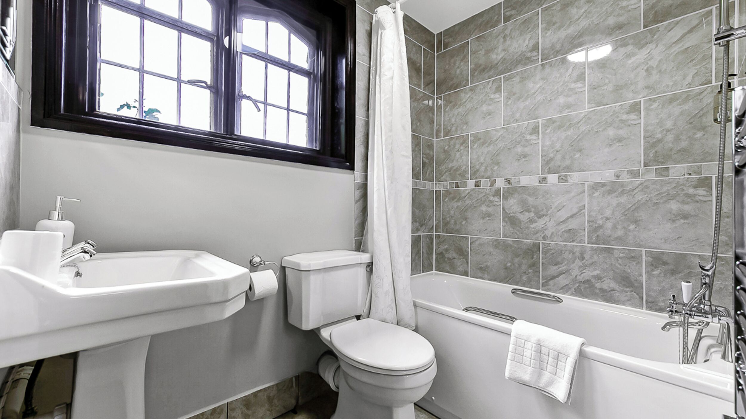 Et badeværelse med vask, toilet og badekar.