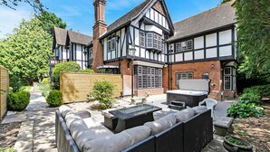 A traditional Tudor-style house with a patio area featuring outdoor furniture and a hot tub. - Tudor Grange (Bournemouth)