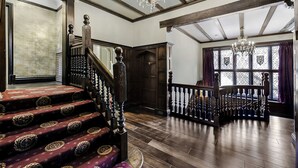 A grand staircase with ornate balusters, a chandelier, and a wooden railing. - Tudor Grange (Bournemouth)
