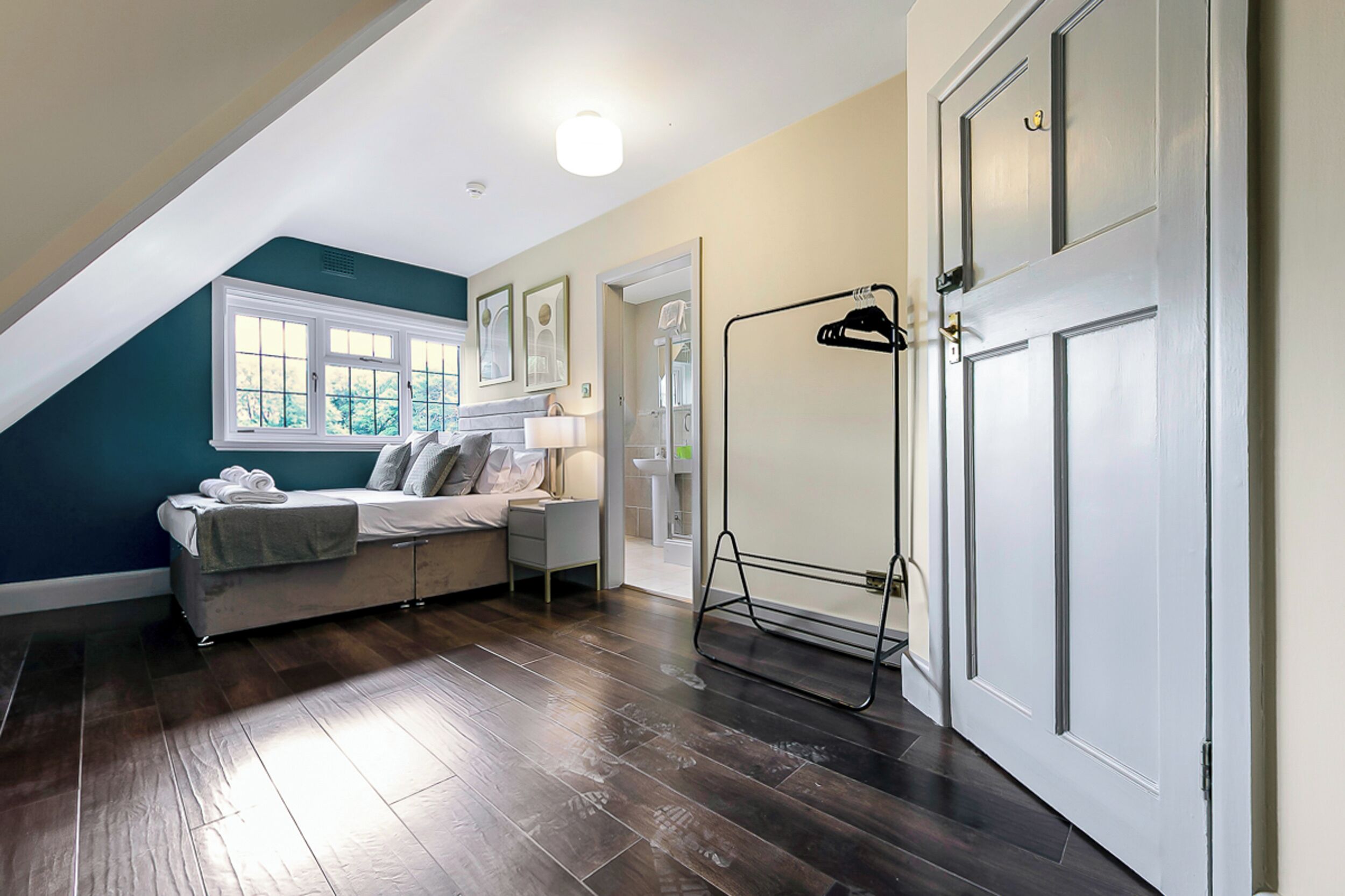 A bedroom with a bed, a nightstand, a window, and a door.