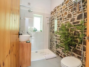 A bathroom with a stone wall, a wooden door, a white sink, and a shower. - Burlodge (Barnstaple)