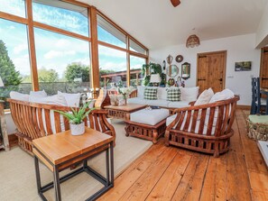 A wooden-floored living room with a large window, a sofa, and a dining table.