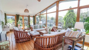 Une pièce lumineuse, avec des meubles en bois, de grandes fenêtres et un ventilateur de plafond.