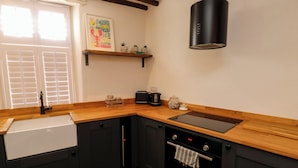 Una cocina moderna con encimera de madera, armarios negros, horno empotrado y campana extractora negra.
