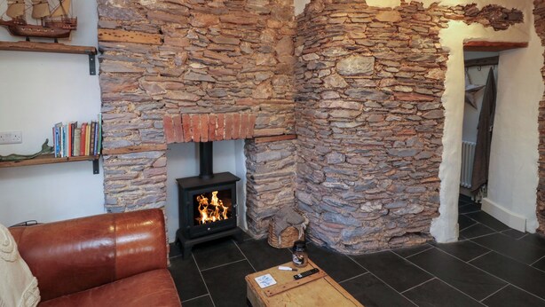 Una sala de estar acogedora con chimenea de piedra, un sofá de cuero, una mesa de centro y una estantería.