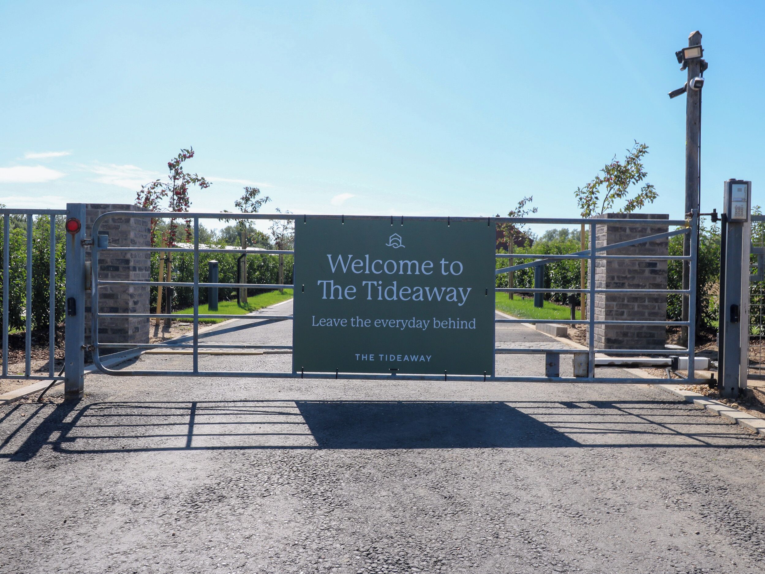 A gated entrance with a sign welcoming visitors to The Tideaway, featuring a clear pathway and a brick structure.