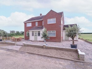 A two-story brick house with a front porch, a small attached garage, and a paved driveway. - The Farmhouse (Clacton-on-Sea)