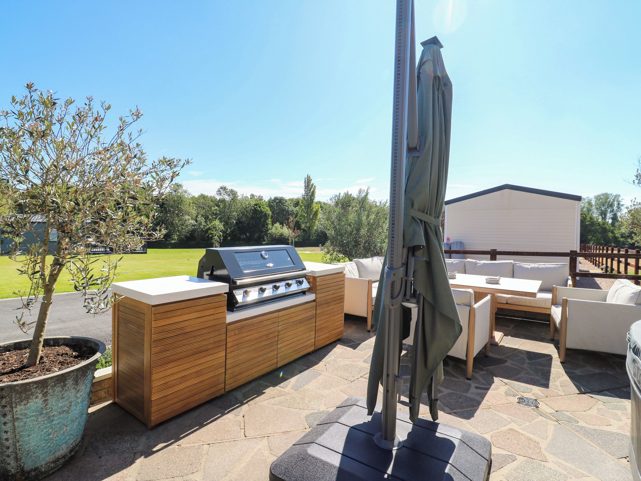 Eine Terrasse im Freien mit einem Grill, einer Sitzecke und einem Blumentopf.