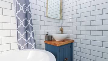 A bathroom with white subway tiles, a white sink, a blue cabinet, and a patterned shower curtain.