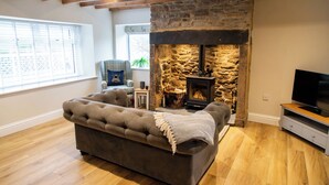 Una sala de estar acogedora con chimenea de piedra, un sofá cómodo y un televisor sobre un mueble de madera.