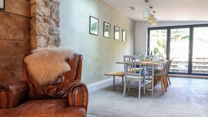 A dining area with a stone wall, wooden table, and chairs. - 28 Fore Street (Seaton)